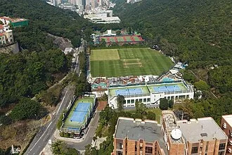 HKCC changed playing locations (2 of 2), Since 1975, HKCC has operated from a custom-designed location near Happy Valley. Photo above shows the Club viewed from the south, with the greens for lawn bowls and croquet visible adjacent to the cricket ground. The club tennis courts are elevated on rooftops (seen in blue above).