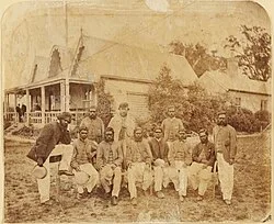 Aboriginal cricket team with captain-coach Tom Wills, December 1866. In the background is the original MCC pavilion, built in 1854.